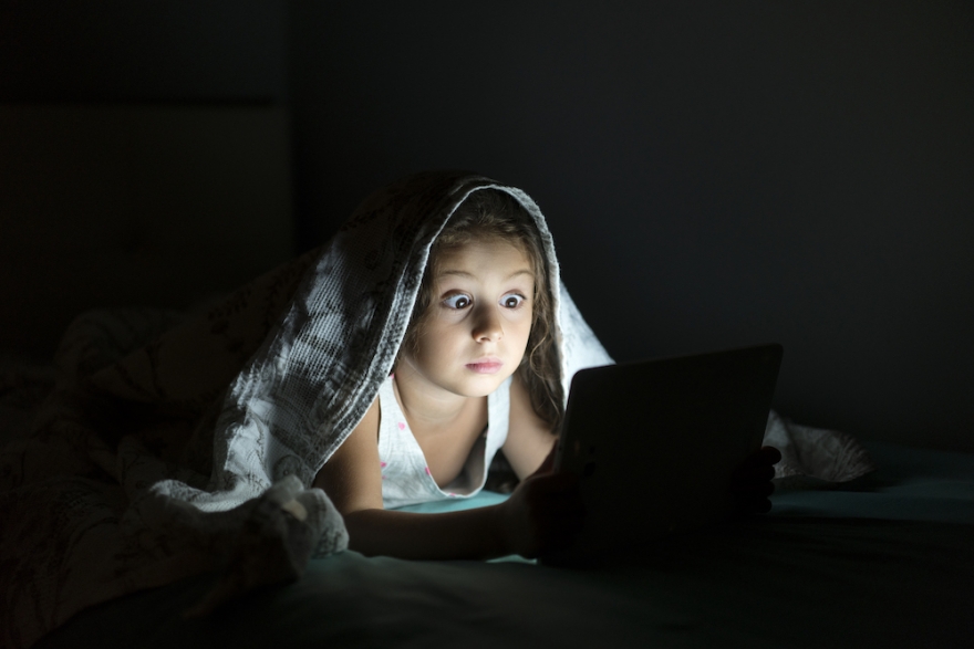 Little girl reading a book in bed late at night