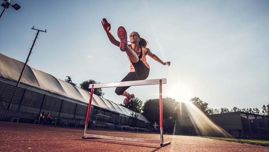 woman jumping over hurdles