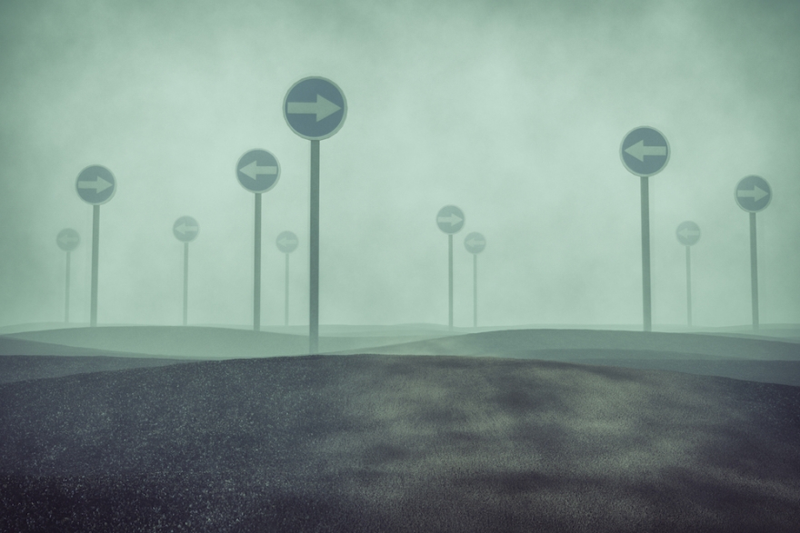 Direction signs looming out of the fog
